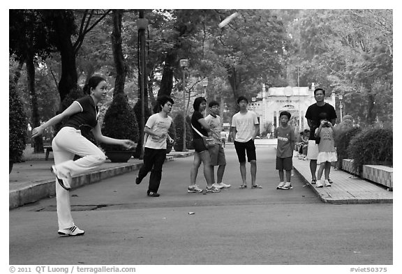 Young woman playing footbag as audience watches, Cong Vien Van Hoa Park. Ho Chi Minh City, Vietnam