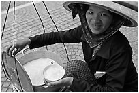 Woman smiling while handling bowl of soft tofu. Ho Chi Minh City, Vietnam ( black and white)