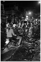 Couple riding motorcycle on flooded street at night. Ho Chi Minh City, Vietnam ( black and white)