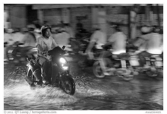 Man riding motorbike on flooded street seen against riders going in opposite direction. Ho Chi Minh City, Vietnam