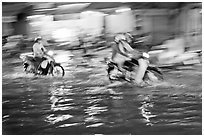 Motion-blured exposure of riders on flooded street at night. Ho Chi Minh City, Vietnam ( black and white)