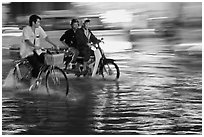 Bicyle and motorbike riders on monsoon-flooded street. Ho Chi Minh City, Vietnam (black and white)
