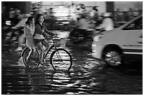 Women sharing a bicycle ride at night on a water-filled street. Ho Chi Minh City, Vietnam ( black and white)