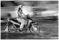 Woman riding on water-filled street, and light streaks. Ho Chi Minh City, Vietnam ( black and white)