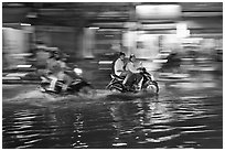 Motorcycles riding through the water on street with motion. Ho Chi Minh City, Vietnam ( black and white)