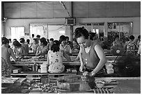 Woman cutting strips of coconut candy in factory. Ben Tre, Vietnam ( black and white)