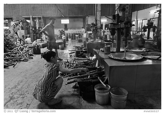 Woman feeding furnace in cococut candy factory. Ben Tre, Vietnam