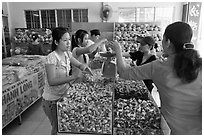 Women weighting coconut candy in retail store. Ben Tre, Vietnam ( black and white)