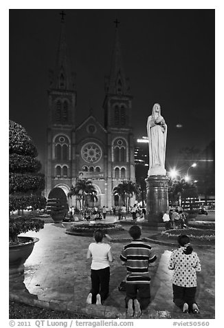 Family in prayer outside Notre-Dame Basilica at night. Ho Chi Minh City, Vietnam