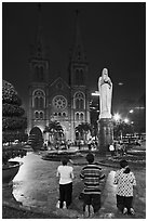 Family in prayer outside Notre-Dame Basilica at night. Ho Chi Minh City, Vietnam ( black and white)