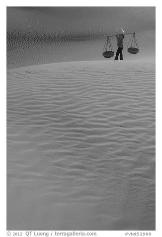 Figure with conical hats and two baskets on sand dunes. Mui Ne, Vietnam (black and white)