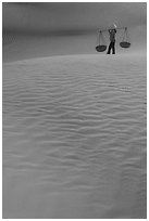 Figure with conical hats and two baskets on sand dunes. Mui Ne, Vietnam ( black and white)