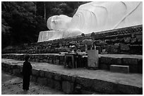 Woman prays below reclining Buddha statue. Ta Cu Mountain, Vietnam ( black and white)