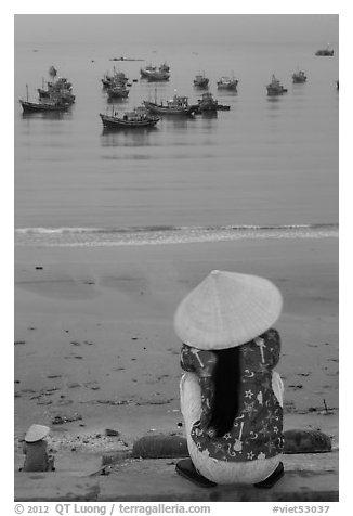 Woman with conical hat sitting above fishing fleet. Mui Ne, Vietnam (black and white)