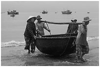 Fishermen carry round woven boat to shore. Mui Ne, Vietnam ( black and white)