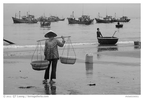 Woman with yoke baskets on beach. Mui Ne, Vietnam