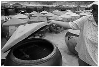 Woman examining vat of fish sauch. Mui Ne, Vietnam ( black and white)