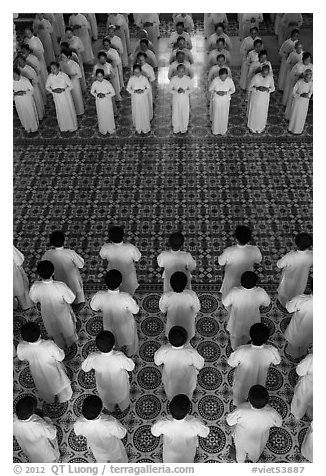 Men and women dressed in white stand in opposing rows in Cao Dai temple. Tay Ninh, Vietnam (black and white)