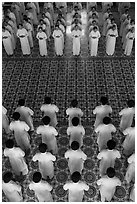 Men and women dressed in white stand in opposing rows in Cao Dai temple. Tay Ninh, Vietnam ( black and white)