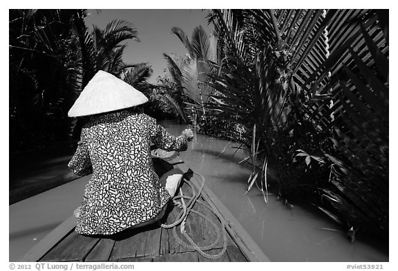 Woman rowing boat in canal lined up with vegetation, Phoenix Island. My Tho, Vietnam (black and white)