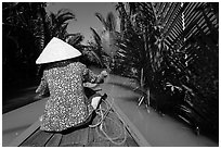 Woman rowing boat in canal lined up with vegetation, Phoenix Island. My Tho, Vietnam ( black and white)