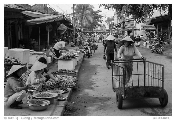 Woman pushing cart on market street. Hoi An, Vietnam (black and white)