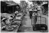 Woman pushing cart on market street. Hoi An, Vietnam ( black and white)