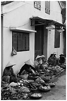 Vegetable vendors sitting in front of old house. Hoi An, Vietnam (black and white)