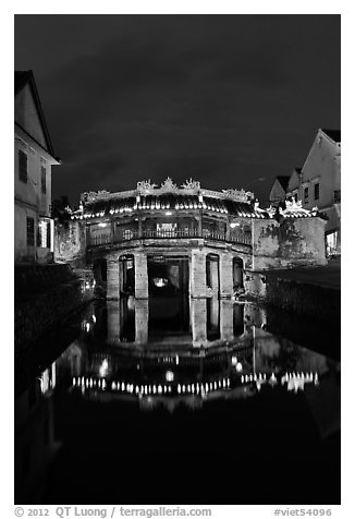 Illuminated Japanese covered bridge reflected in canal. Hoi An, Vietnam (black and white)