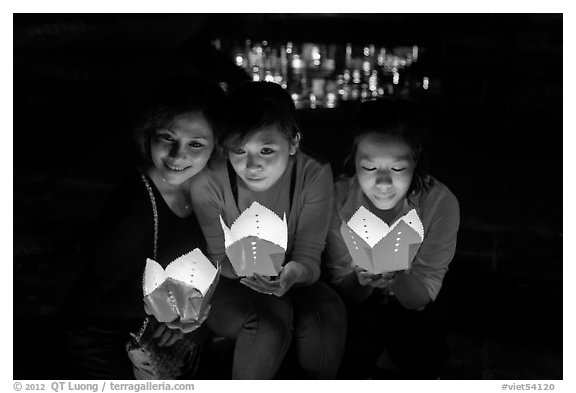 Faces of three women in the glow of candle boxes. Hoi An, Vietnam