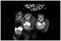 Faces of three women in the glow of candle boxes. Hoi An, Vietnam ( black and white)