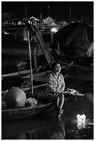 Woman sitting in boat with floating candles by night. Hoi An, Vietnam ( black and white)