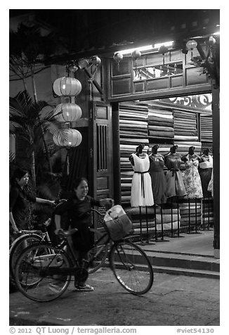 Women with bicycles in front of taylor shop. Hoi An, Vietnam (black and white)