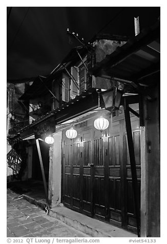 Townhouse with wooden doors lighted by paper lanterns. Hoi An, Vietnam (black and white)