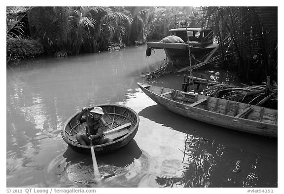 Man rows coracle boat in river channel. Hoi An, Vietnam