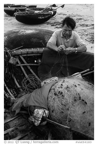 Fisherman repairing net on beach. Da Nang, Vietnam (black and white)