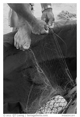 Close-up of hands and feet of man mending net. Da Nang, Vietnam