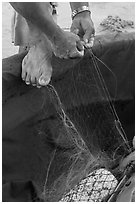 Close-up of hands and feet of man mending net. Da Nang, Vietnam ( black and white)