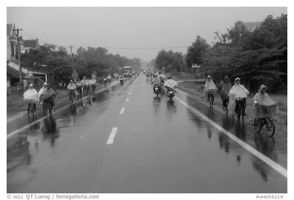 Riders wearing colorful ponchos on wet road on Hwy 1 south of Hue. Vietnam (black and white)