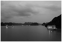 View of bay with lights of anchored tour boats at dawn. Halong Bay, Vietnam (black and white)