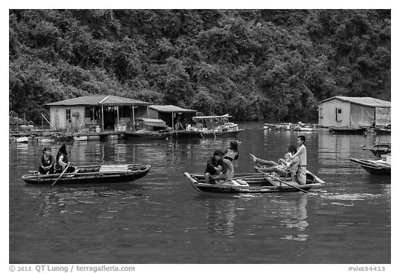 Villagers move between floating houses by rowboat. Halong Bay, Vietnam