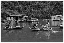 Villagers move between floating houses by rowboat. Halong Bay, Vietnam ( black and white)