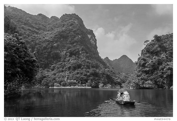 Boat journeying below tall lush cliffs, Trang An. Ninh Binh,  Vietnam