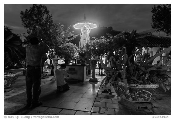 Men pray at outside Phung Son Pagoda at night, district 11. Ho Chi Minh City, Vietnam (black and white)