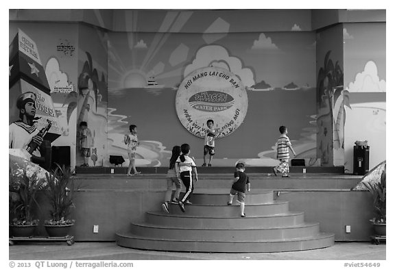 Children on stage next to militaristic mural, Dam Sen Water Park, district 11. Ho Chi Minh City, Vietnam (black and white)