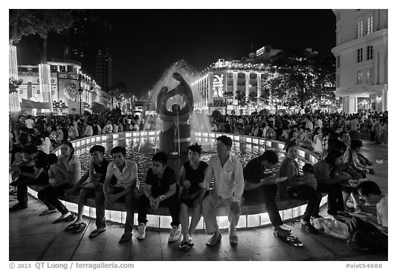 People sitting on fountain at night, New Year eve. Ho Chi Minh City, Vietnam
