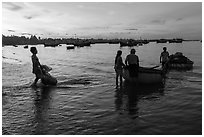 Fishermen using coracle boats to transport cargo at dawn. Mui Ne, Vietnam ( black and white)