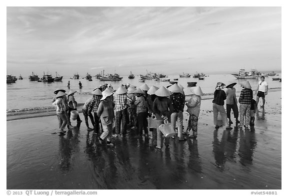 Women gather on beach to collect freshly caught fish. Mui Ne, Vietnam (black and white)
