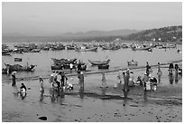 Hawkers gather on mirror-like beach in early morning. Mui Ne, Vietnam ( black and white)