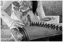 Close up of hands playing plucked zither. My Tho, Vietnam ( black and white)